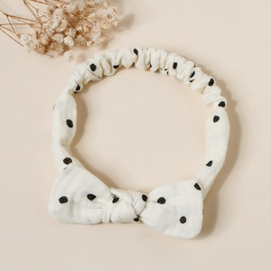 Detailed view of cream elastic cotton headband with black polka dots and a bow knot