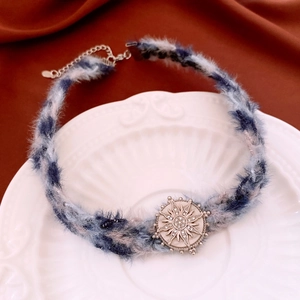 Détail du collier choker en peluche avec pendentif soleil en strass sur une assiette