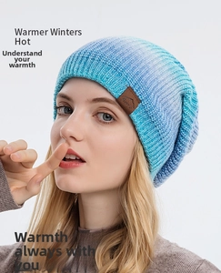 Détail du bonnet en maille dégradé bleu et blanc avec un écusson logo en cuir brun