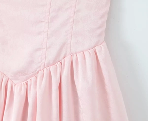 Détail du tissu jacquard rose et design plissé à taille haute sur une robe douce