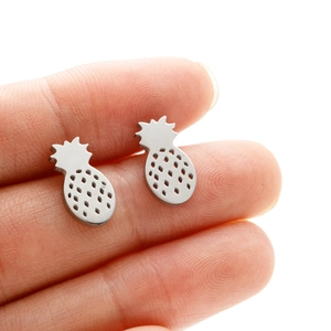 Polished stainless steel pineapple stud earrings shown on fingertip for scale
