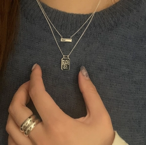 Detail of layered 925 sterling silver necklaces with engraved plaques on female model