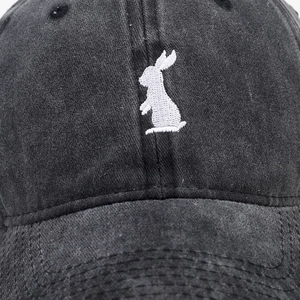 Close-up of white rabbit embroidery on vintage washed cotton baseball cap texture
