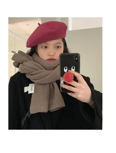 Close-up of thick ribbed knit scarf in camel with a trendy burgundy wool beret hat