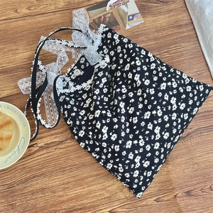 Detailed close-up of floral canvas bag with white lace bow and magnetic snap closure