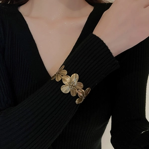 Macro detail of vintage gold floral open cuff bracelet with textured flower petals
