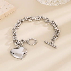 Detail of silver stainless steel heart pendant bracelet with OT toggle clasp on desk