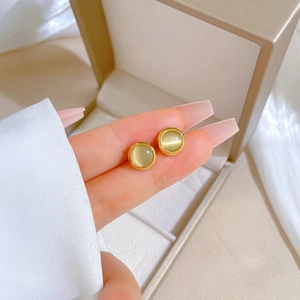 Macro shot of titanium steel round cat eye stud earrings held against a jewelry box