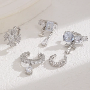 Detail view of five silver-tone zircon ear cuffs with snowflake and cross pendants
