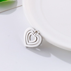 Minimalist stainless steel hollow heart pendant on a white plate with green accents