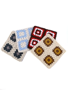 Macro view of four colorful handmade crochet floral coasters with intricate stitching