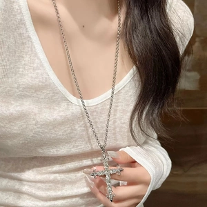 Close-up of a vintage silver cross pendant necklace with rhinestones on a female model