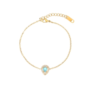 Macro view of gold chain bracelet featuring a pear-cut blue zircon pendant with halo