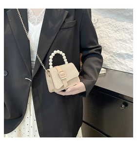 Detail of elegant beige crossbody bag featuring pearl handle and sparkling sequin flap