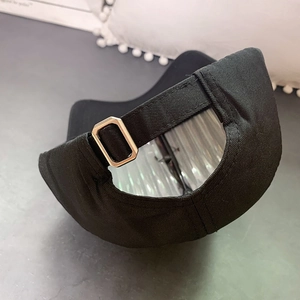 Detail of adjustable metal buckle and strap on the back of a black cotton baseball cap