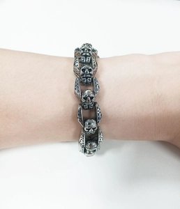 Detailed view of a Gothic stainless steel skull link bracelet worn on a male wrist