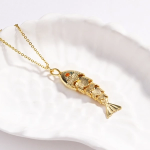 Detail of a golden koi fish pendant with orange gemstone eye and scales on a white shell