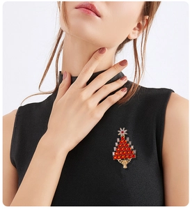 Detail of a Christmas tree brooch with red faux gemstones and a gold-toned alloy base