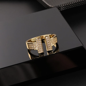 Detailed view of golden T-shaped open ring with micro-pave zircons on a reflective surface