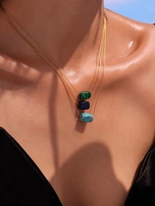 Close-up of layered gold chain necklace featuring turquoise and lapis square pendants