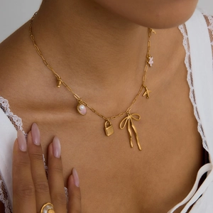 18K gold stainless steel necklace with pink bow shell charms on a female model