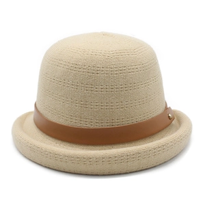 Detailed macro of beige knitted bucket hat featuring a brown leather strap and gold rivet