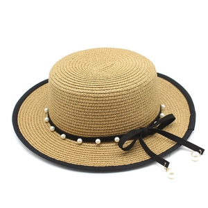 Detail of wheat straw boater hat with black ribbon, white pearls and elegant bow
