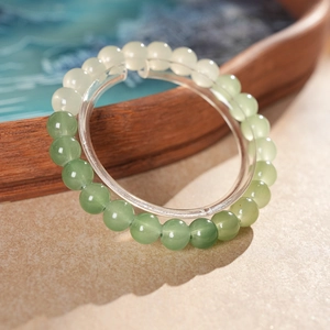 Close-up of beaded gemstone bracelet with natural green gradient beads on a wooden tray