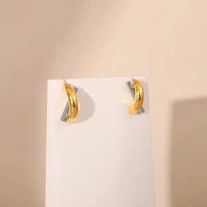 Minimalist gold and silver two-tone crisscross X-shaped stud earrings on white stand
