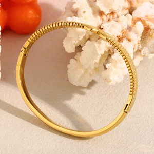 Detail of 18K gold plated stainless steel hinge bangle with snakeskin texture and coral