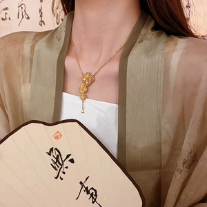 Detail of gold floral tassel necklace with three filigree flowers on a Chinese style model