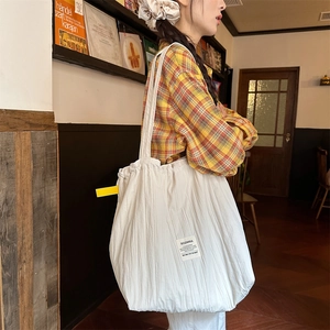 Detailed texture of white pleated tote bag with yellow accent label and brand tag