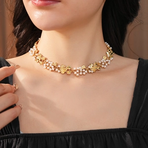Close-up of a vintage golden necklace featuring delicate metal leaves and white pearls