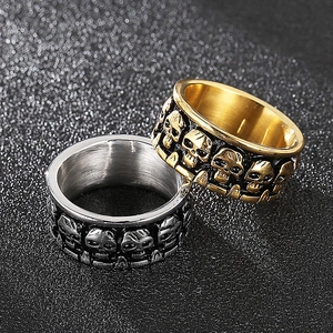 Macro detail of gold and silver skull punk rings on a dark textured background