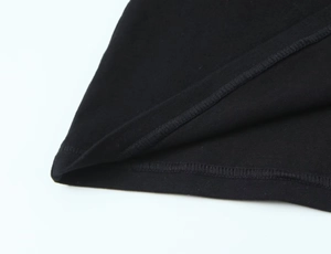 Gros plan du tricot en coton noir montrant les coutures précises sur l'ourlet du t-shirt