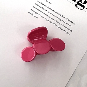 Detail showing smooth pink resin hair claw clip placed on a book page background