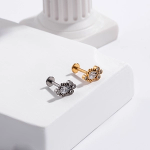 Close-up of gold and silver G23 titanium ear studs with teardrop and round zircon inlay