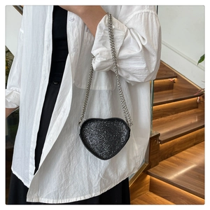 Detail of a sparkling black heart-shaped crossbody bag with silver metal chain strap