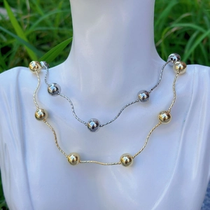 Polished 18k gold and silver bead chain necklaces displayed on a minimalist bust model