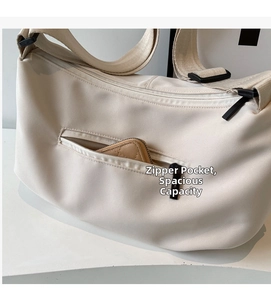 Detail of cream nylon crossbody bag showing the front zipper pocket and strap design