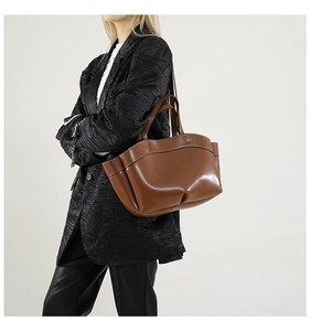 Borsa tote in pelle marrone con esclusivo design a pieghe sul fondo indossata da modella