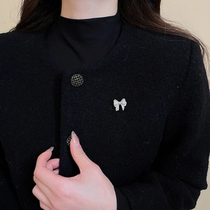 Close-up of a silver bow brooch with sparkling cubic zirconia on a black jacket collar