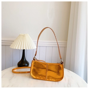 Détail d'un sac orange métallique en simili cuir avec rivets sur une table en marbre