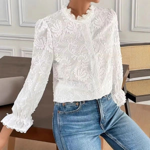 Détails d'une élégante chemise blanche avec broderie florale et col montant à volants
