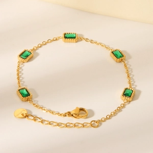 Detailed view of gold plated stainless steel bracelet with green rectangular zircons