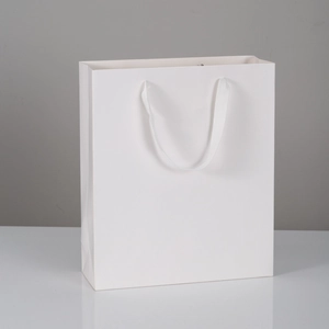 Sacchetto regalo minimalista in carta bianca con manici in nastro su superficie lucida