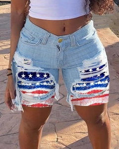 Detailed close-up of distressed denim shorts with American flag patch under the ripped denim