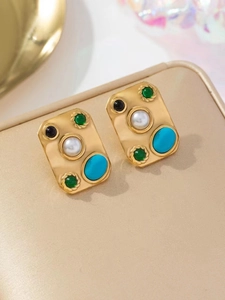 Boucles d'oreilles vintage en or avec pierres colorées et perles sur support beige