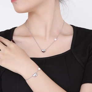 Ensemble bijoux pendentif cœur argenté et perles porté par un mannequin élégant