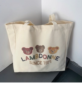 Close-up of three colorful cartoon bears embroidery on creamy white canvas tote bag